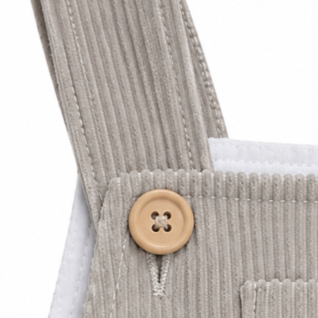 Detalle de los tirantes, los botones de madera natural y el bolsillo central del peto de pana beige de alta calidad.