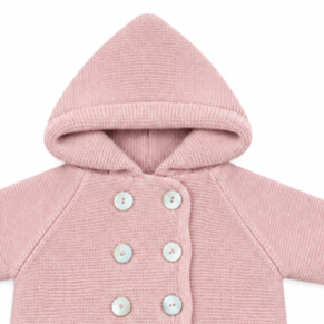 Detalle en primer plano de la capucha integrada, la textura del punto y los botones nacarados delanteros de la chaqueta San Francisco en color rosa maquillaje.