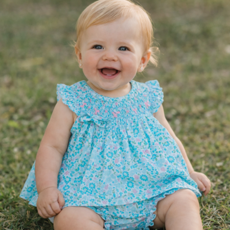 Bebé de 6 meses con jesusito Rocío de algodón liberty azul, con bordado nido de abeja hecho a mano y cubrepañal a juego.