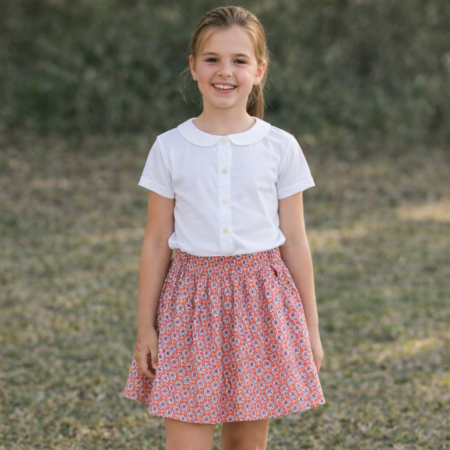 Niña con falda Romisa de algodón combinada con blusa, conjunto clásico de moda infantil.