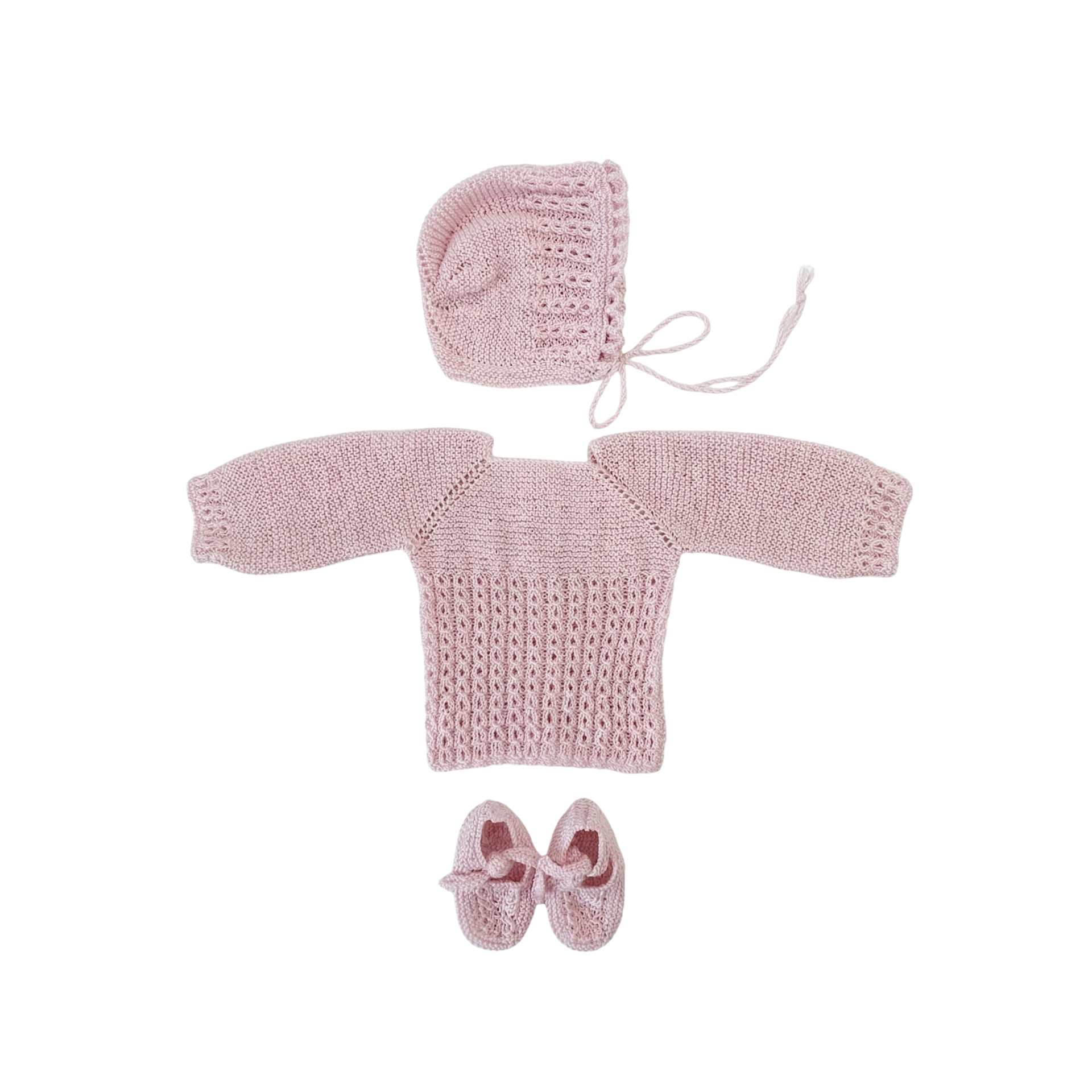 Alt: Conjunto de primera puesta para recién nacido de la marca Machu, compuesto por jersey de punto calado rosa, capota y patucos artesanos en 100% algodón.