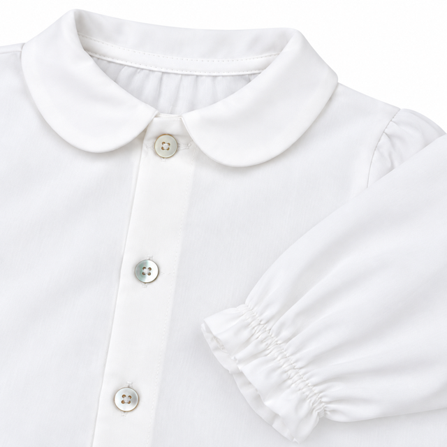 Detalle cercano del cuello , los botones nacarados y el puño fruncido de la blusa de algodón unisex.