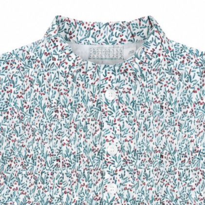 Detalle cercano del cuello alzado, los botones delanteros y el delicado tejido de algodón con motivos florales de la blusa Virginia.