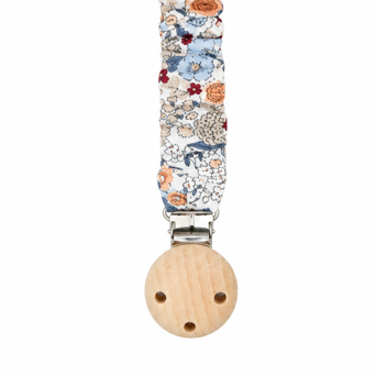 Detalle en primer plano de la cinta fruncida de algodón con estampado floral y la pinza con pieza redonda de madera natural.